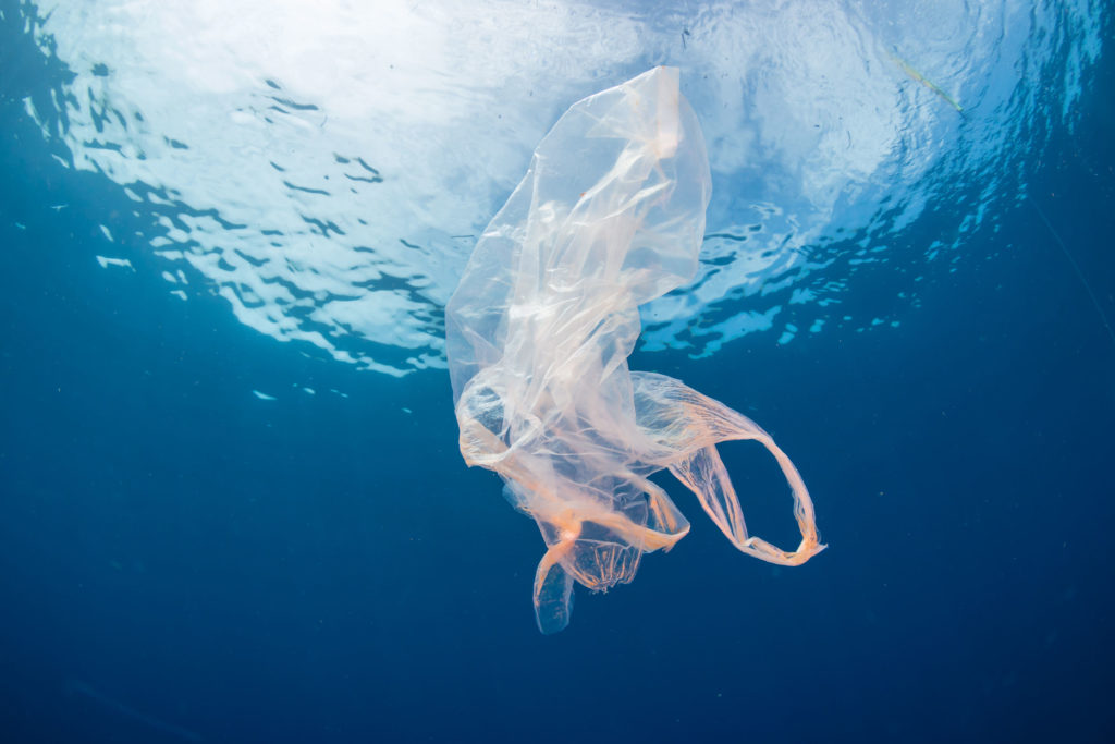 Plastic pollution:- A discarded plastic bag floats in a clear, b Plastic pollution:- A discarded plastic bag floats in a clear, b