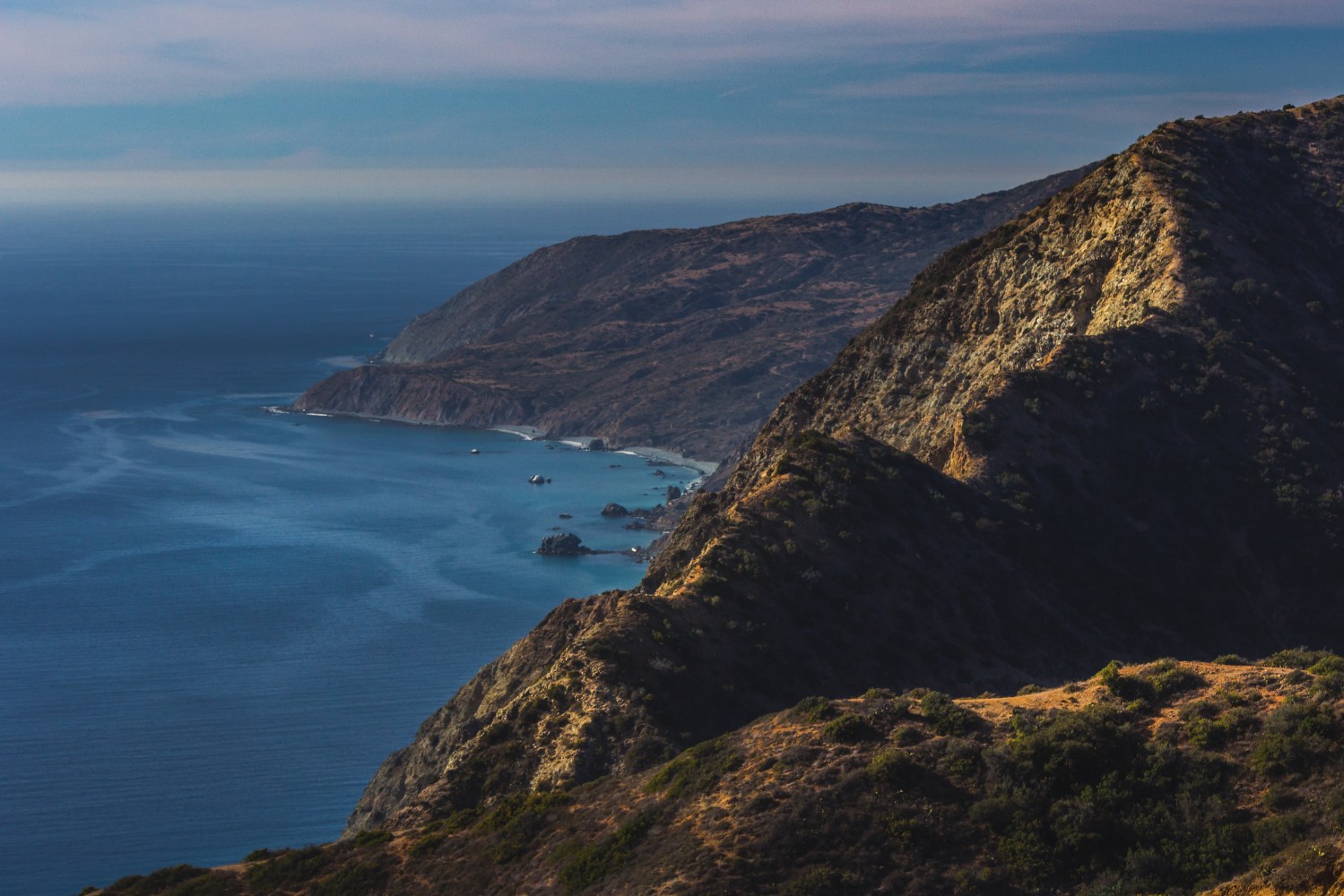 Stunning mountaintop view of rugged Catalina coastline and canyons on a sunny day with clouds in the sky and beautiful blue water, Catalina Island, California