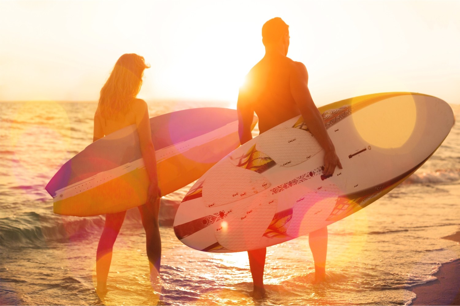 two people walking with surfboards by the ocean