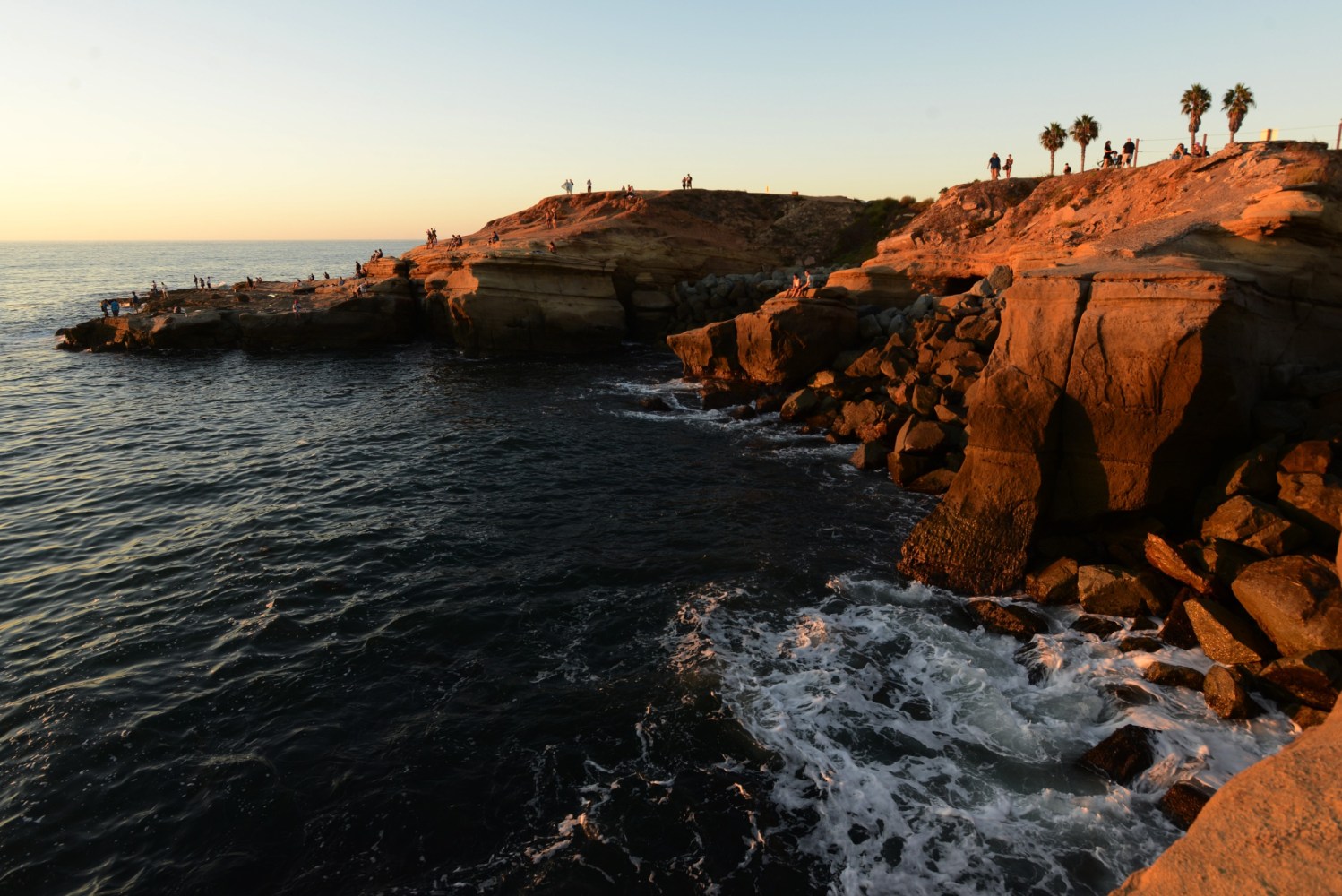 a group of people on a rock near the ocean
