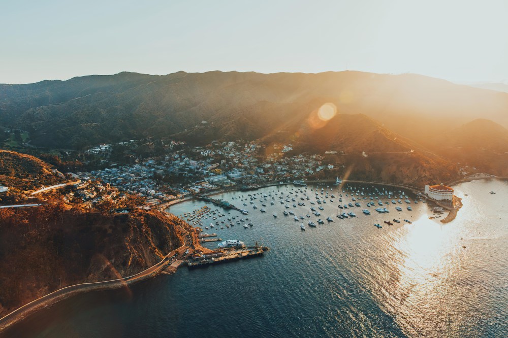 Aerial view of a coastal town with boats in the bay during sunset.
