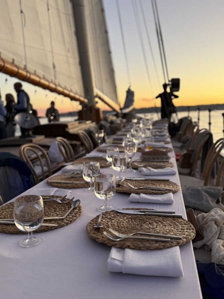 Elegant table setting with wicker placemats on a sailboat at sunset.