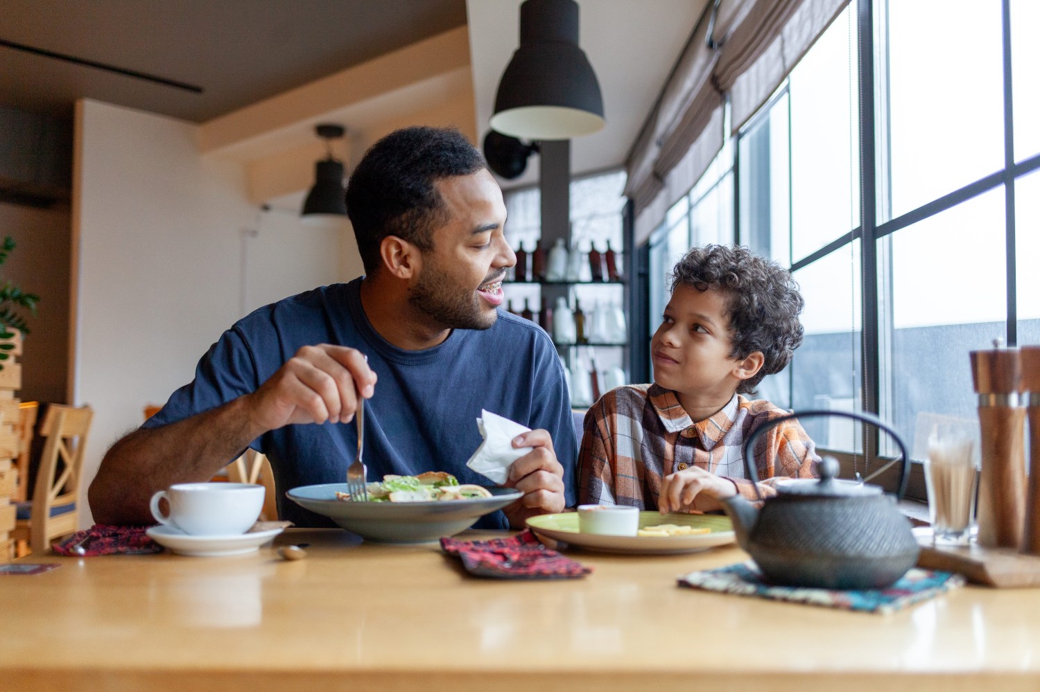 Father and son enjoying a meal together at a dining table.